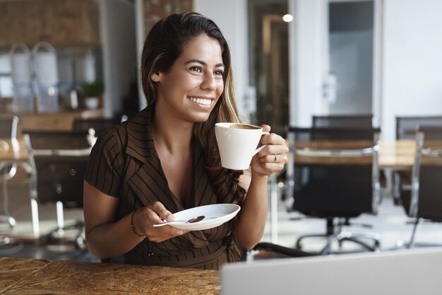 Stilvolle gut aussehende Bürodame, die heißen Kaffee hält Tasse sitttin allein im Café sitzend