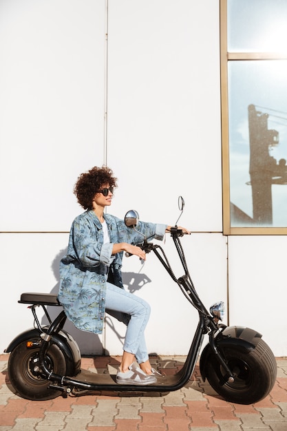 Stilvolle junge Frau, die auf einem modernen Motorrad sitzt