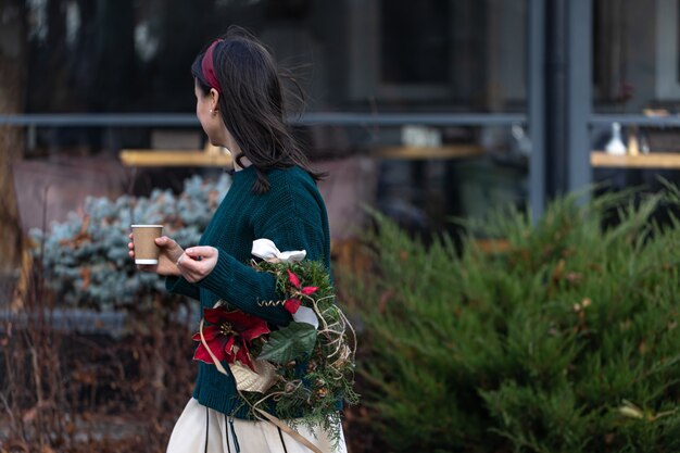 Stilvolle junge Frau, die nach dem Weihnachtseinkauf Kaffee genießt.