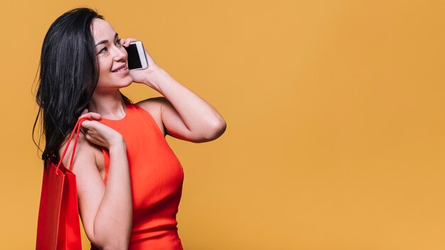 Stilvolle junge Frau mit der Tasche, die am Telefon plaudert