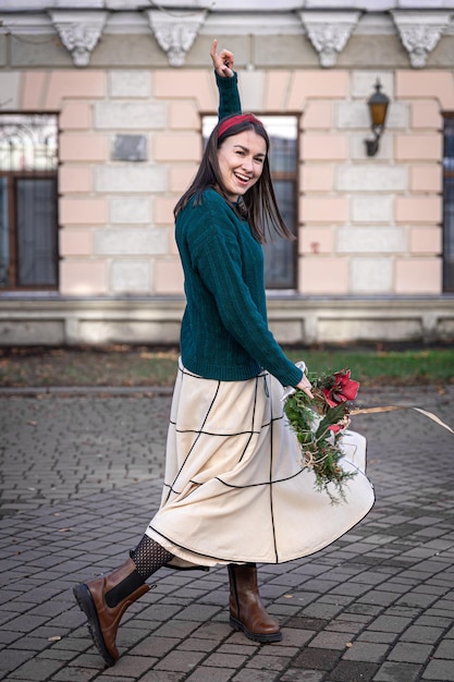 Stilvolle junge Frau mit Weihnachtskranz draußen wartet auf Weihnachten