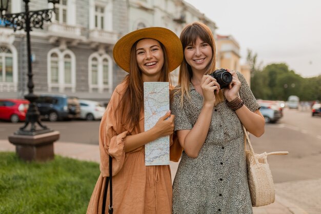 Stilvolle junge Frauen, die zusammen in Europa reisen, gekleidet in trendigen Frühlingskleidern und Accessoires