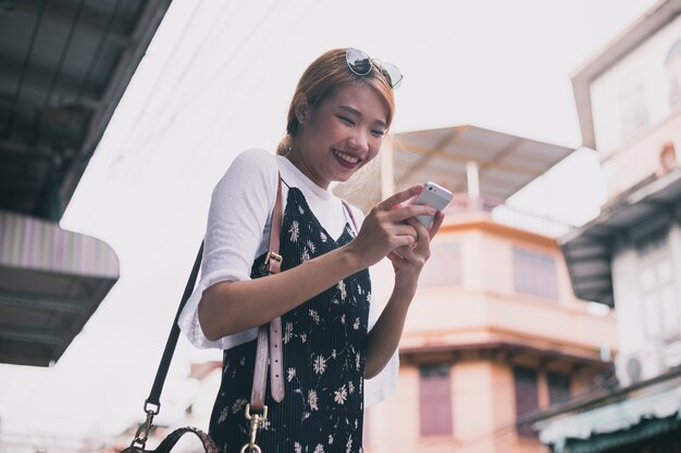 Stilvolle lachende Frau mit Smartphone draußen