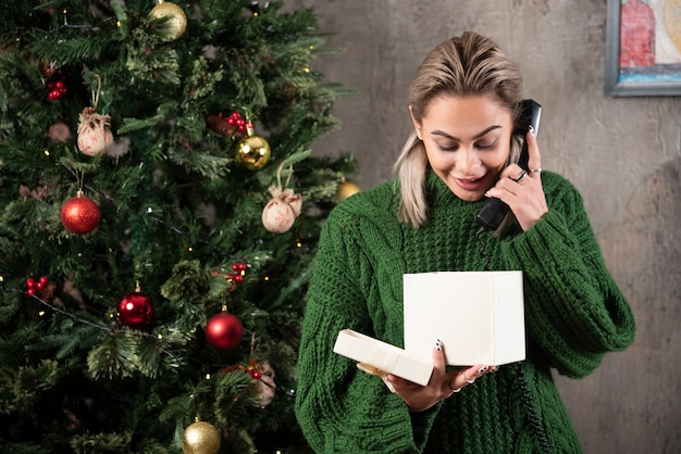 Stilvolle modische Frau im grünen Pullover, der am Telefon spricht