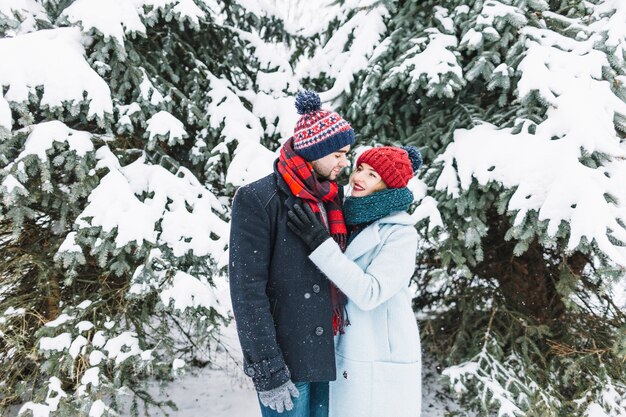 Stilvolle Paare, die im schneebedeckten Park stehen