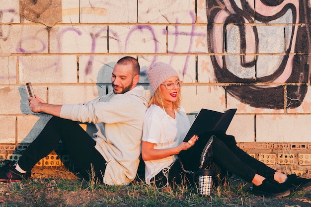 Kostenloses Foto stilvolle paare mit buch und gerät draußen