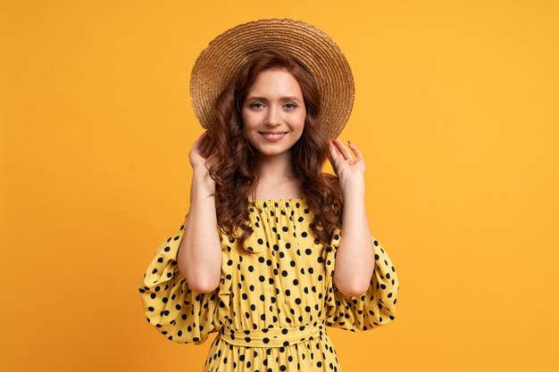 Stilvolle rothaarige Frau posiert im gelben Kleid mit Ärmeln auf Gelb. Sommerstimmung.