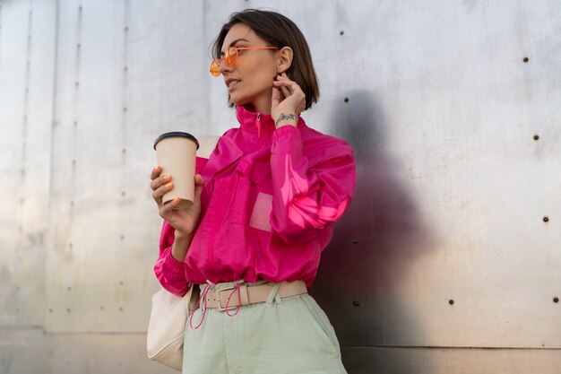 Stilvolle sportliche Frau mit kurzer Frisur, die mit Kaffeetasse aufwirft