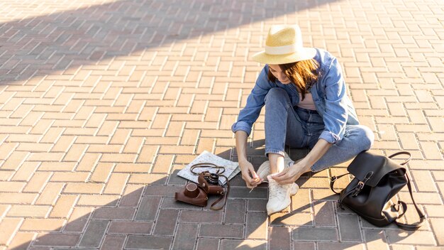 Stilvolle Touristin mit Hut, der ihre Schnürsenkel bindet