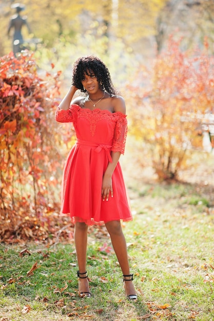 Kostenloses Foto stilvolle, trendige, lockige afro-frankreich-frau posierte am herbsttag in rotem kleid schwarzafrikanisches weibliches modell