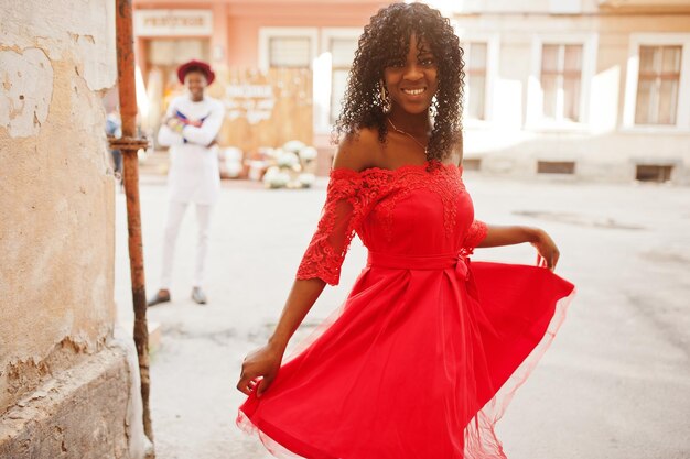 Stilvolle, trendige, lockige Afro-Frankreich-Frau posierte am Herbsttag in rotem Kleid Schwarzafrikanisches weibliches Modell