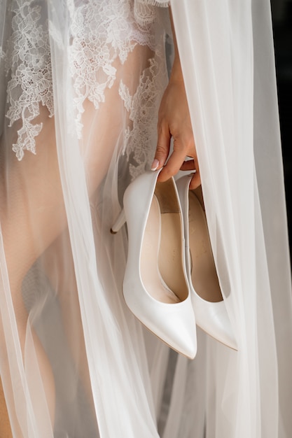 Stilvolle weiße Hochzeitsschuhe in der Hand der Braut