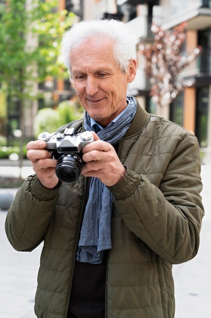 Stilvoller älterer Mann in der Stadt, der mit der Kamera Fotos macht