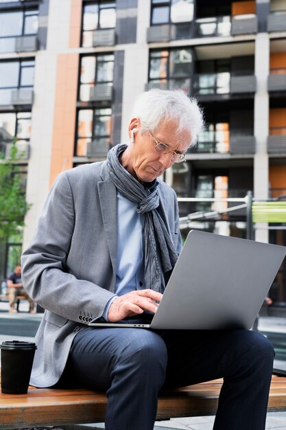 Stilvoller älterer Mann in der Stadt mit Laptop