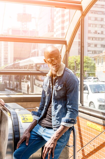 Stilvoller afrikanischer junger Mann, der am Eingang der U-Bahn in der Stadt sitzt