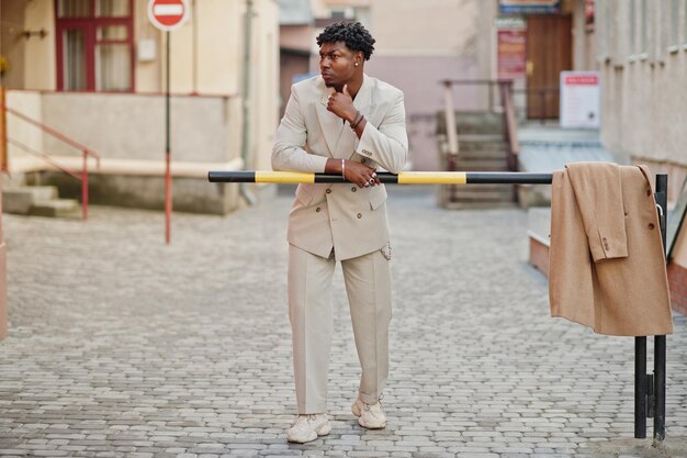 Stilvoller Afro-Mann in beigefarbenem Anzug der alten Schule Modischer junger afrikanischer Mann in Freizeitjacke auf nacktem Oberkörper