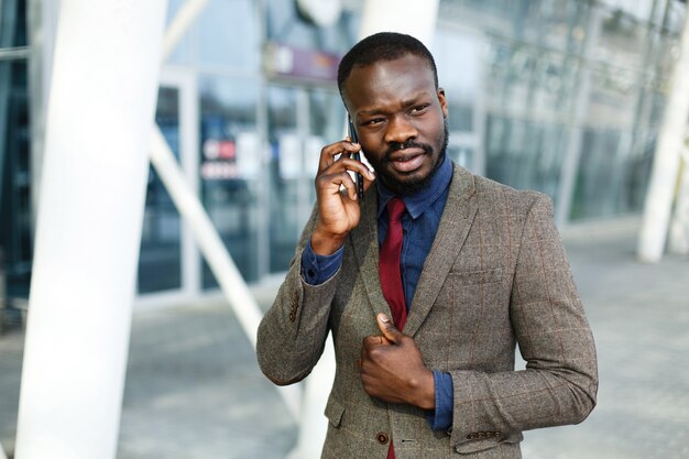 Stilvoller Afroamerikanerschwarzgeschäftsmann spricht auf seinem Smartphone