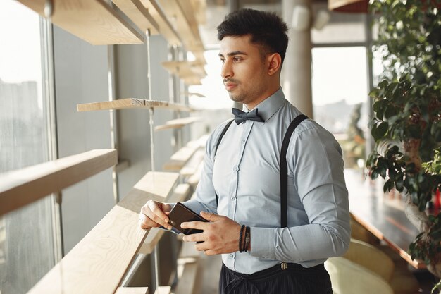 Stilvoller Geschäftsmann, der in einem Büro arbeitet und das Telefon benutzt