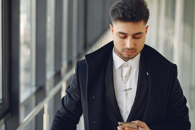 Stilvoller Geschäftsmann, der in einem Büro arbeitet und das Telefon benutzt