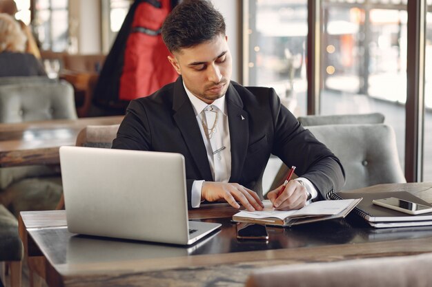 Stilvoller Geschäftsmann, der in einem Café arbeitet und den Laptop benutzt