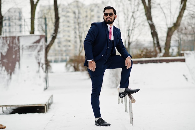 Stilvoller indischer Bartgeschäftsmann in Anzug und Sonnenbrille posierte am Wintertag im Freien