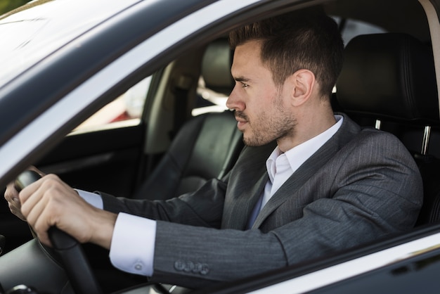 Stilvoller junger Geschäftsmann, der Auto fährt