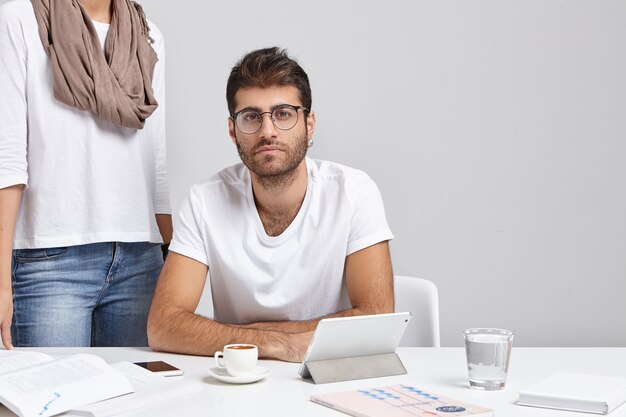 Kostenloses Foto stilvoller junger mann, der am schreibtisch sitzt