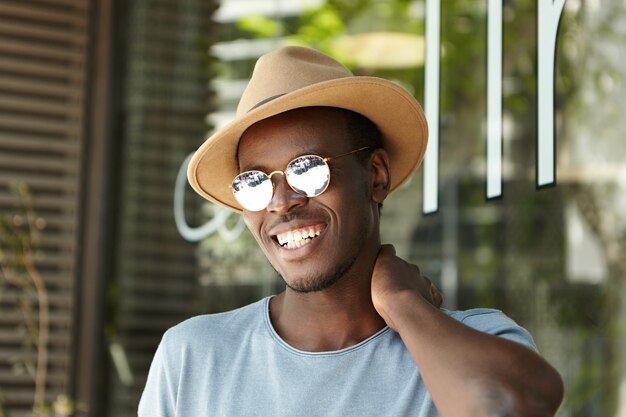 Stilvoller junger Mann, der Hut und Sonnenbrille trägt