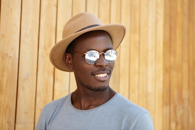 Stilvoller junger Mann, der Hut und Sonnenbrille trägt