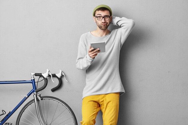 Stilvoller junger Mann, der nahe Fahrrad steht