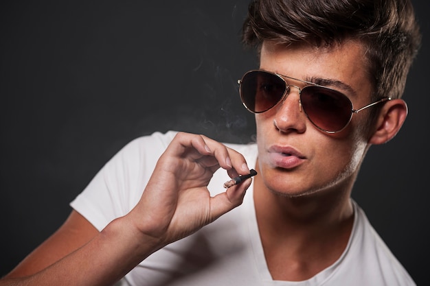 Stilvoller junger mann, der zigarette raucht