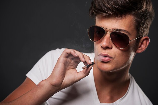 Stilvoller junger Mann, der Zigarette raucht