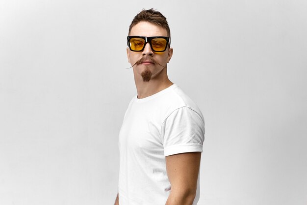 Stilvoller junger Mann mit Sonnenbrille und weißem T-Shirt, das ein Auge versteckt