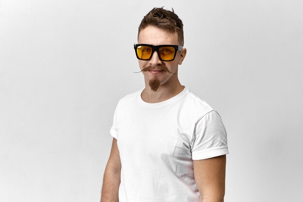 Stilvoller junger Mann mit Sonnenbrille und weißem T-Shirt, das ein Auge versteckt