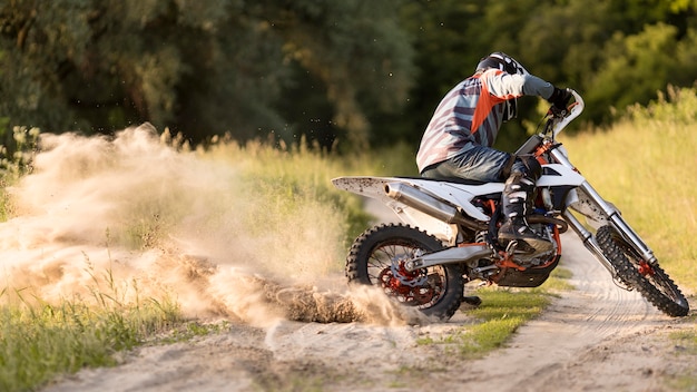 Kostenloses Foto stilvoller mann, der motorrad im wald reitet