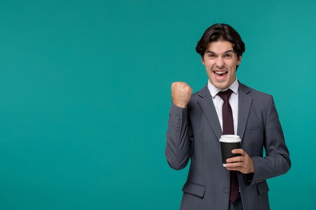 Stilvoller netter gutaussehender Mann des Geschäftsmannes im grauen Büroanzug und -krawatte aufgeregt mit der Kaffeetasse