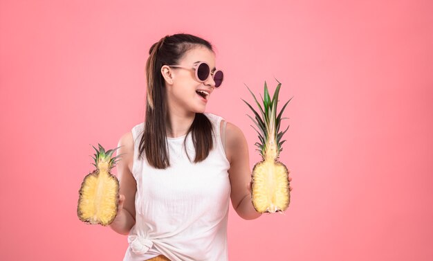 Stilvolles junges Mädchen in der Sonnenbrille lächelt und hält Früchte. Sommerferienkonzept.