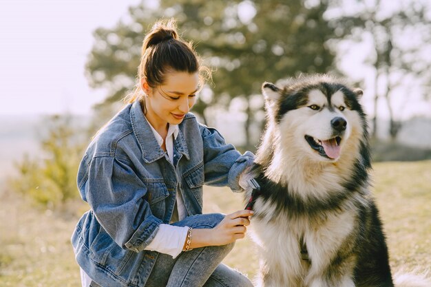 Stilvolles Mädchen in einem sonnigen Feld mit einem Hund