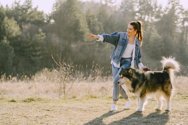 Stilvolles Mädchen in einem sonnigen Feld mit einem Hund