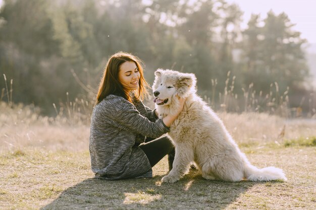 Stilvolles Mädchen in einem sonnigen Feld mit einem Hund