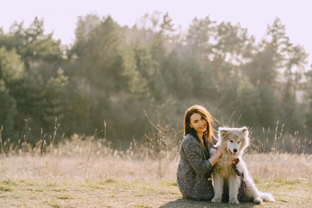 Stilvolles Mädchen in einem sonnigen Feld mit einem Hund