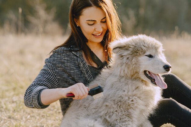 Stilvolles Mädchen in einem sonnigen Feld mit einem Hund