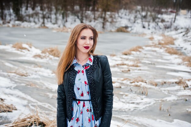 Stilvolles Mädchen in Lederjacke am Wintertag gegen zugefrorenen See