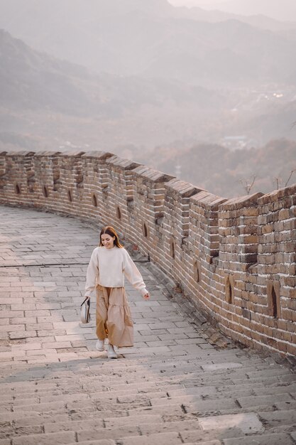 Stilvolles Mädchen, welches die Chinesische Mauer nahe Peking während des Herbstes besucht