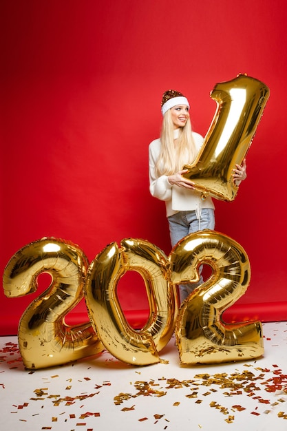 Kostenloses Foto stock foto von attraktiven blonden mädchen in nikolausmütze, pullover und jeans mit ziffer eins in den händen.