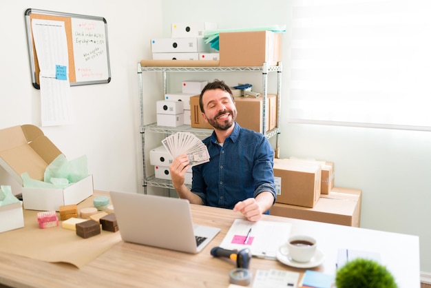 Stolzer Geschäftsinhaber, der mit seinem neuen Startup und E-Commerce viel Geld verdient. Hispanischer Mann, der wegen vieler Kundenaufträge viel Bargeld hält