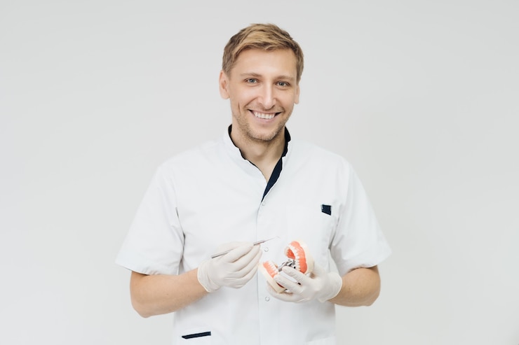 Kostenlose Foto stomatologe arzt erklärt dem patienten, der eine probe des menschlichen kiefers hält, die richtige zahnhygiene