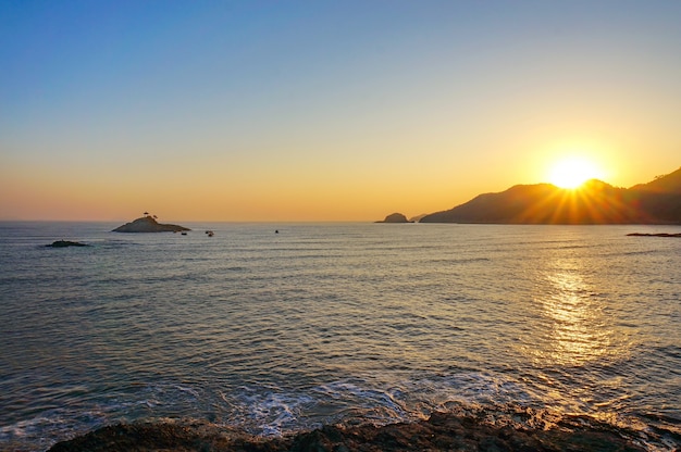 Strand bei Sonnenuntergang mit Bergen