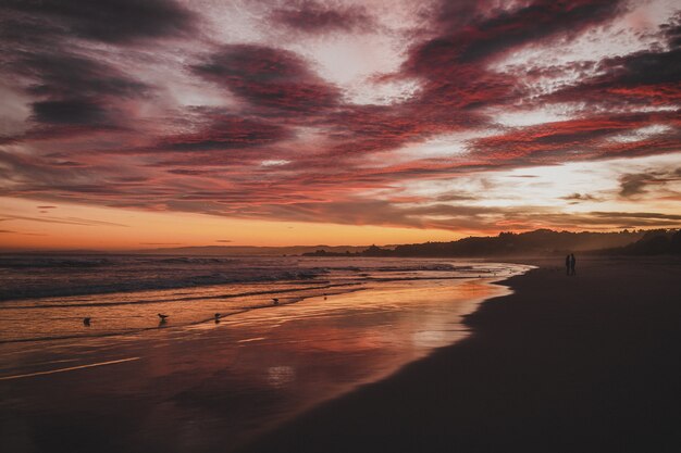 Strand umgeben durch das Meer unter einem bewölkten Himmel während des Sonnenuntergangs in Brighton in Neuseeland