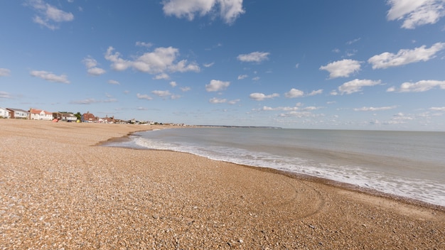 Strand umgeben vom Meer und Gebäuden unter dem Sonnenlicht und einem blauen Himmel am Tag